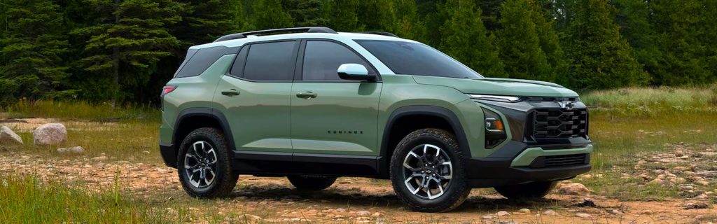Green Chevrolet Equinox SUV parked on a rocky off-road trail with trees in the background.